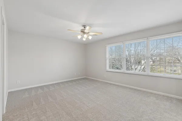 an empty room with windows and chandelier fan