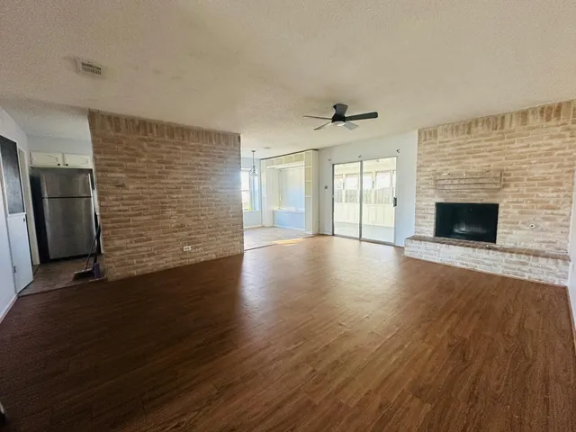 an empty room with wooden floor fireplace and windows