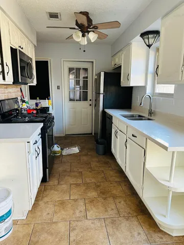 a kitchen with kitchen island granite countertop a sink appliances cabinets and a counter top space