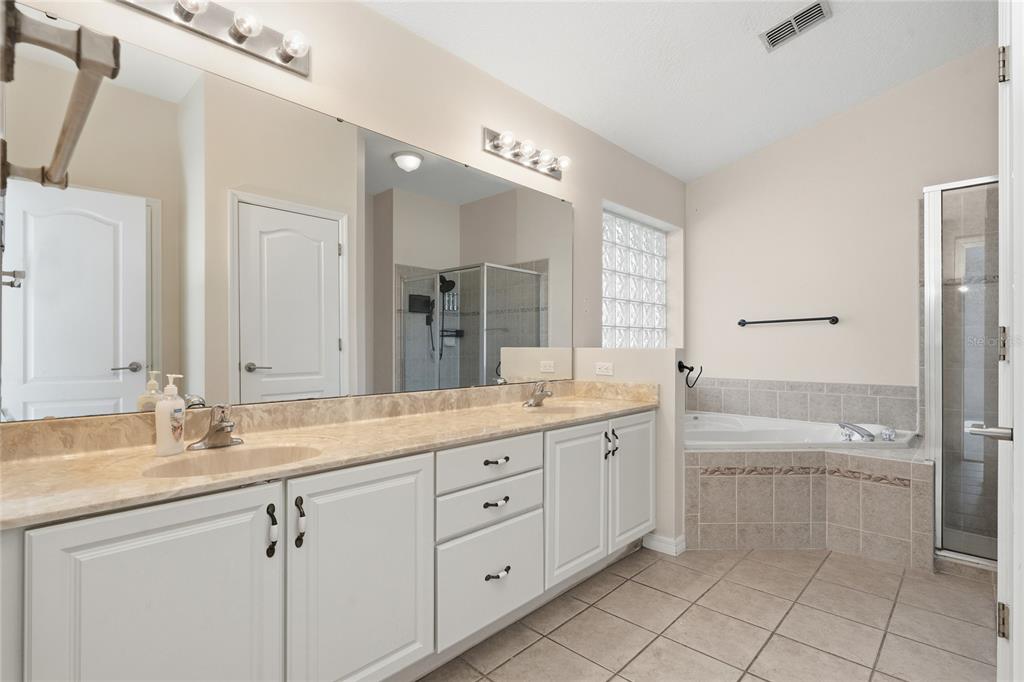 11036 Bronson Road Clermont, FL 34711 - Photo 11 of 29 a spacious bathroom with a granite countertop sink a toilet a mirror and shower