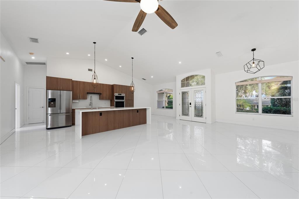 11036 Bronson Road Clermont, FL 34711 - Photo 3 of 29 a large white kitchen with kitchen island a stove a refrigerator a sink and a counter top space