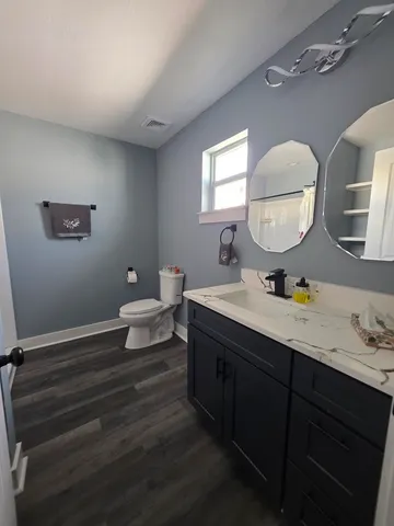 a bathroom with a toilet sink double vanity and mirror