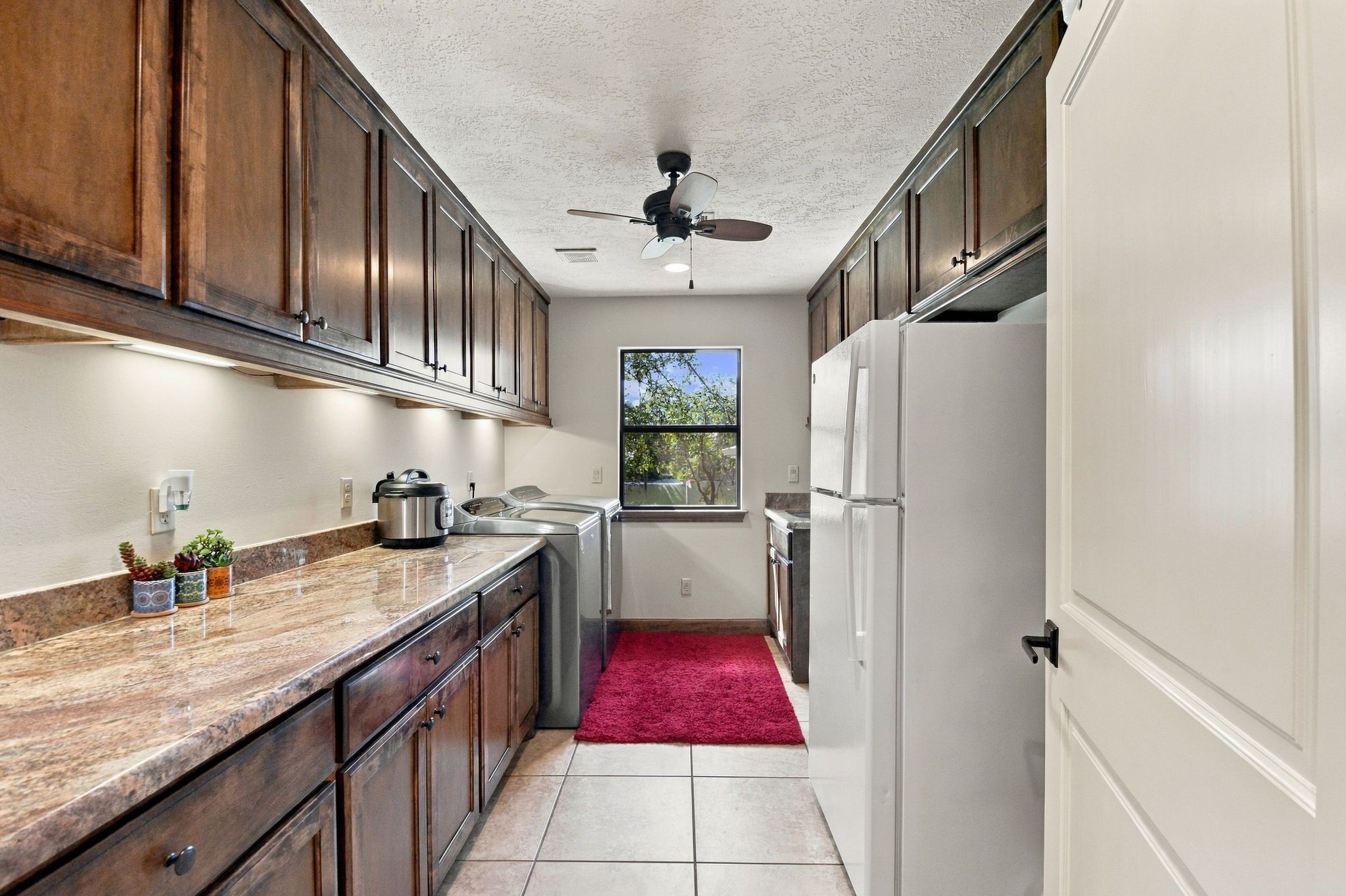 20341 Bay Hill Road Point Blank, TX 77364 - Photo 30 of 50 Spacious laundry room with rich wooden cabinets, sleek granite countertops, and modern appliances, offering ample storage and functionality.