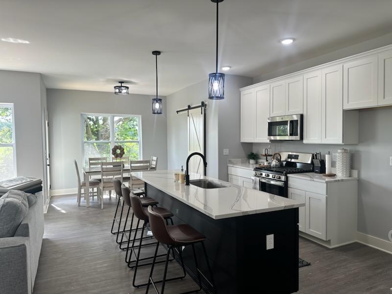 634 Anjali Court, Unit R Sycamore, IL 60178 - Photo 4 of 20 a kitchen with granite countertop a table chairs microwave and cabinets