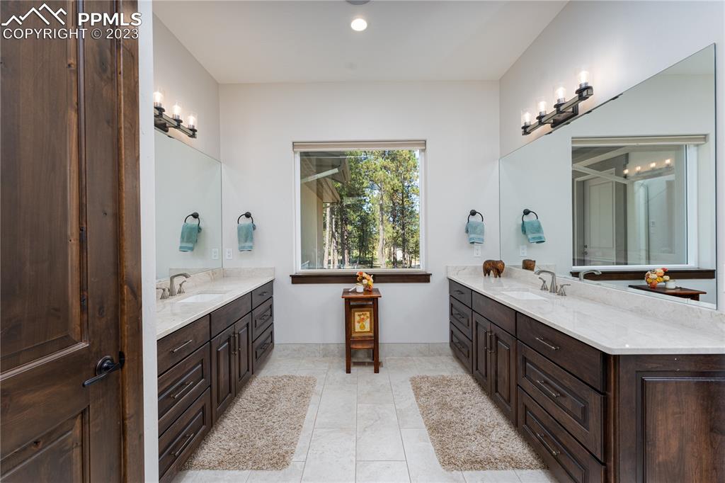 9775 Walker Road Colorado Springs, CO 80908 - Photo 13 of 50 a bathroom with a granite countertop double vanity sink a large mirror a bathtub and window