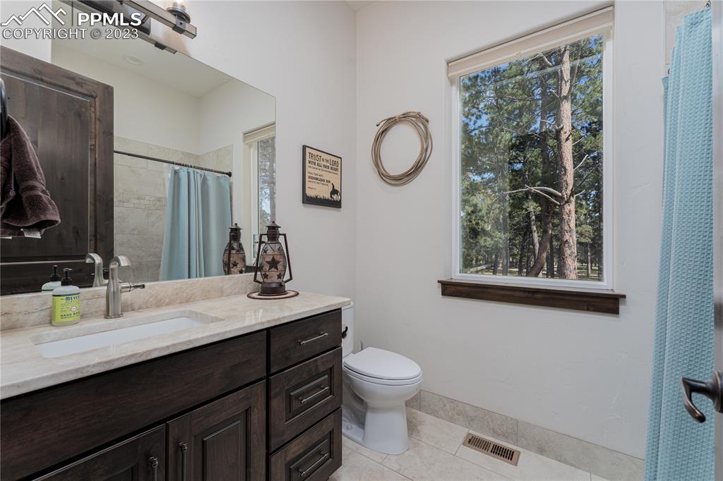 9775 Walker Road Colorado Springs, CO 80908 - Photo 18 of 50 a bathroom with a toilet sink vanity and mirror