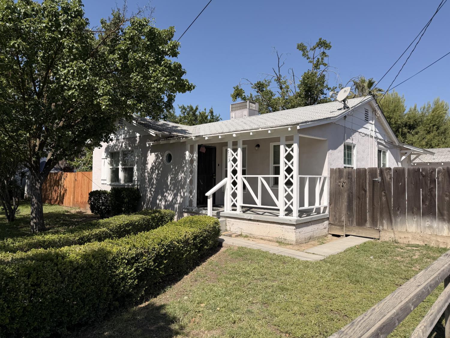713 West 4th Street Madera, CA 93637 - Photo 3 of 28 a view of a white house with a yard and plants
