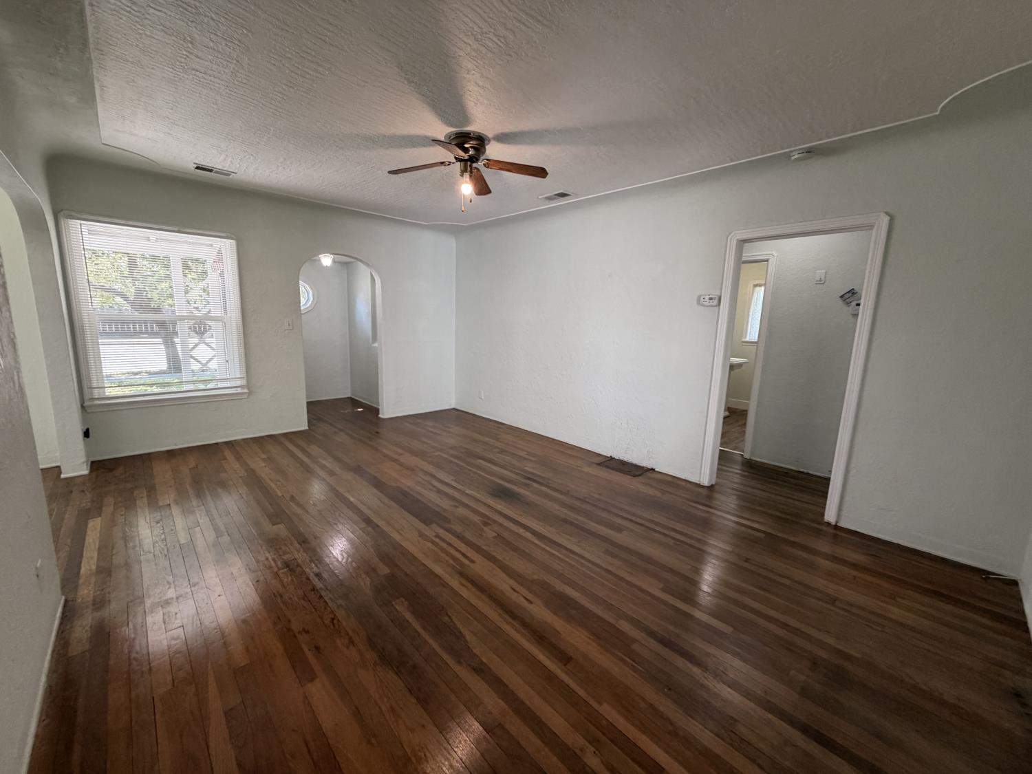 713 West 4th Street Madera, CA 93637 - Photo 10 of 28 an empty room with wooden floor chandelier fan and windows