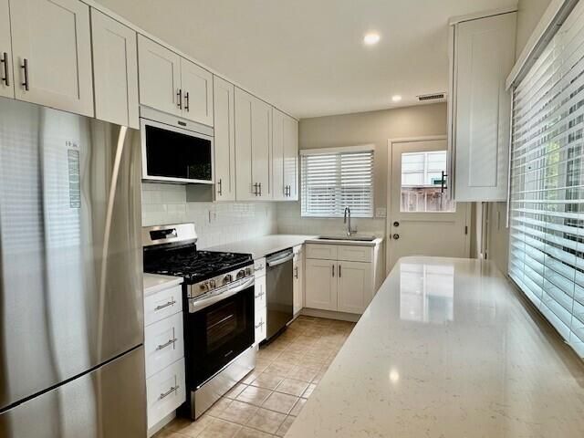 a kitchen with stainless steel appliances a stove sink microwave and cabinets