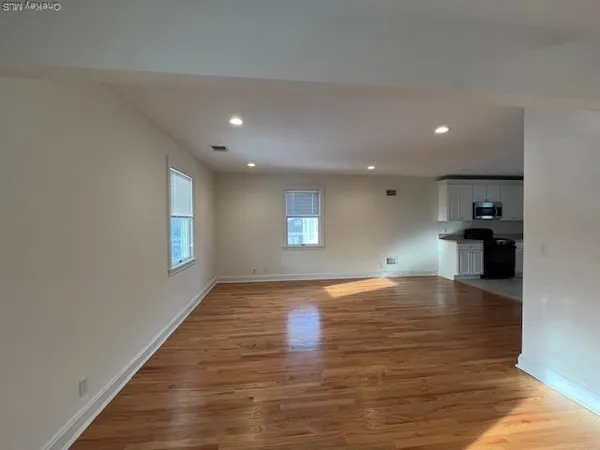 a view of an empty room with window and wooden floor