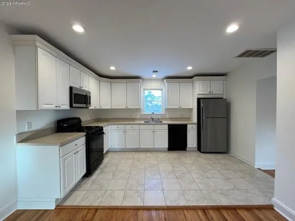 a large kitchen with a large counter top stainless steel appliances and cabinets