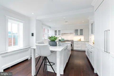 a kitchen with white cabinets and wooden floors