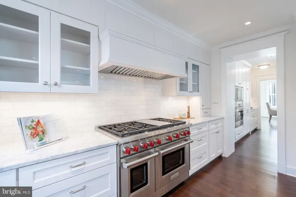 a kitchen with stainless steel appliances a stove and white cabinets with wooden floor