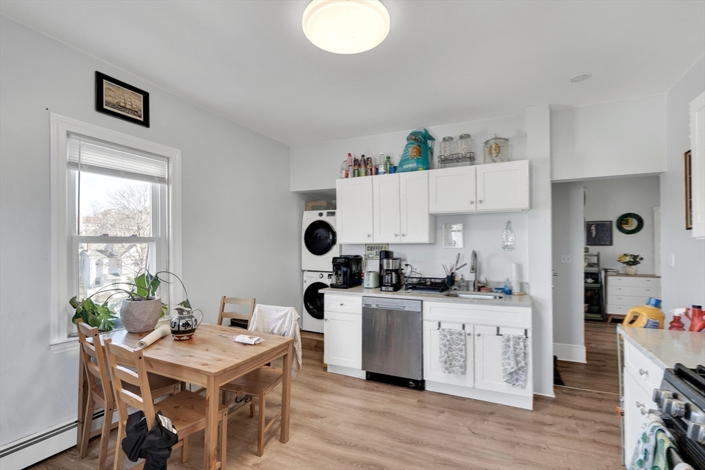 39 Union Street Boston, MA 02135 - Photo 22 of 27 a kitchen with stainless steel appliances a white stove top oven a sink a dining table and chairs with wooden floor