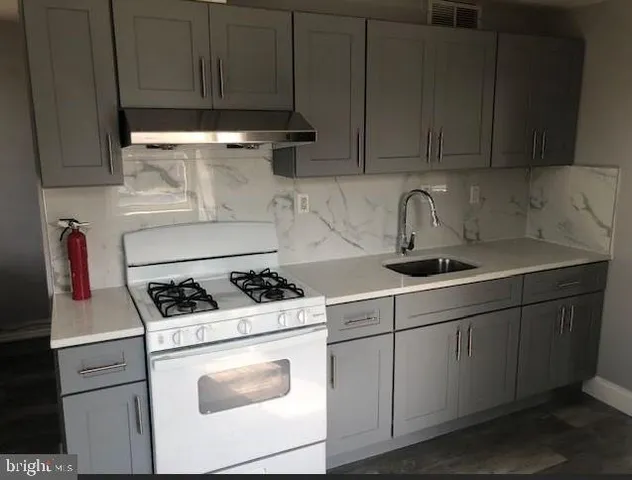 a kitchen with stainless steel appliances granite countertop a sink stove and cabinets