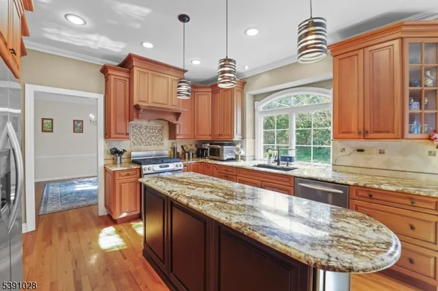 a kitchen with stainless steel appliances granite countertop a sink a stove and a wooden floors