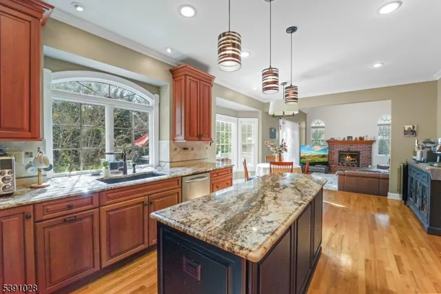 a kitchen with granite countertop a sink dishwasher stove top oven and cabinets with wooden floor