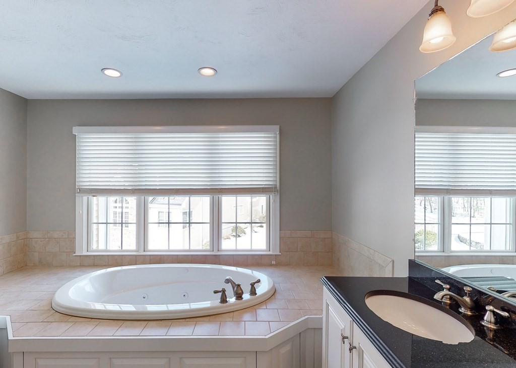 80 Clubhouse Way, Unit 80 Sutton, MA 01590 - Photo 22 of 29 a bathroom with a tub a sink a mirror and a window