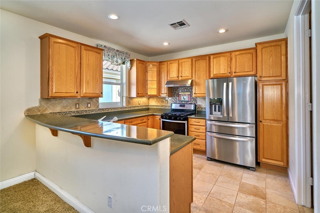 1143 Saguara Road Beaumont, CA 92223 - Photo 38 of 66 a kitchen with stainless steel appliances granite countertop a refrigerator a sink a stove and island