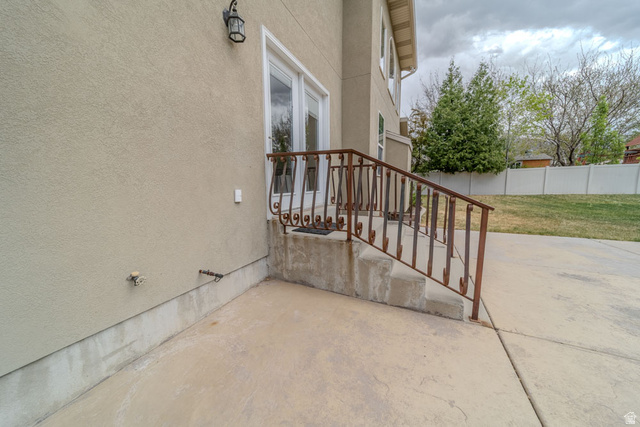 598 Hollow Creek Road Draper, UT 84020 - Photo 96 of 110 Concrete patio with stucco exterior, a decorative wrought iron railing, concrete steps, double glass panel doors, and an outdoor wall lantern