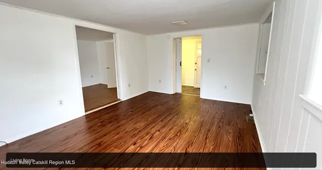 a view of empty room with wooden floor and window
