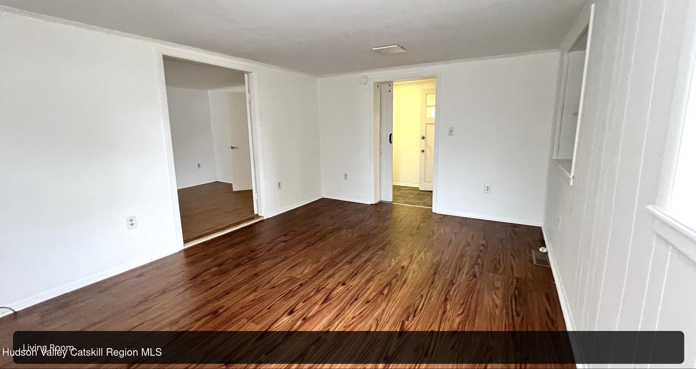 a view of empty room with wooden floor and window