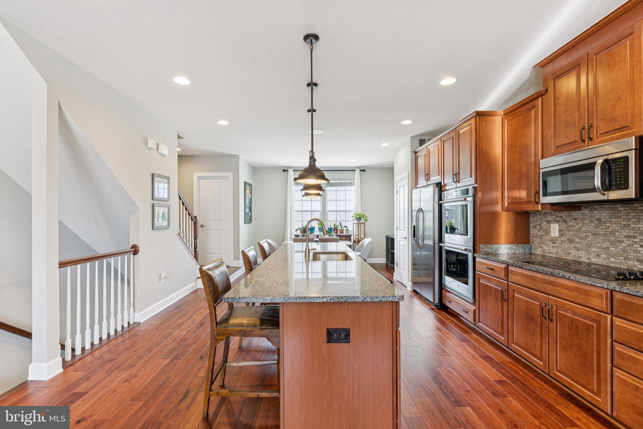 9924 Whitemoss Drive Manassas, VA 20109 - Photo 6 of 43 a kitchen with stainless steel appliances granite countertop a refrigerator a stove top oven a dining table and chairs with wooden floor