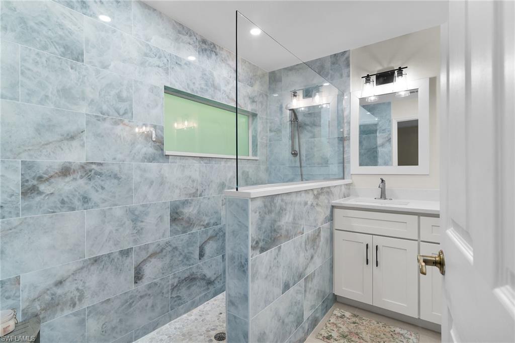789 Coldstream Court Naples, FL 34104 - Photo 16 of 26 a bathroom with a shower sink and mirror