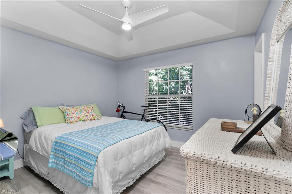 789 Coldstream Court Naples, FL 34104 - Photo 18 of 26 a bedroom with a bed next to a window with a chandelier