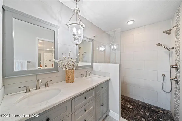 a bathroom with a double vanity sink a toilet a shower and a mirror