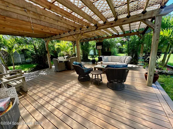 a view of a patio with table and chairs barbeque potted plants and large tree