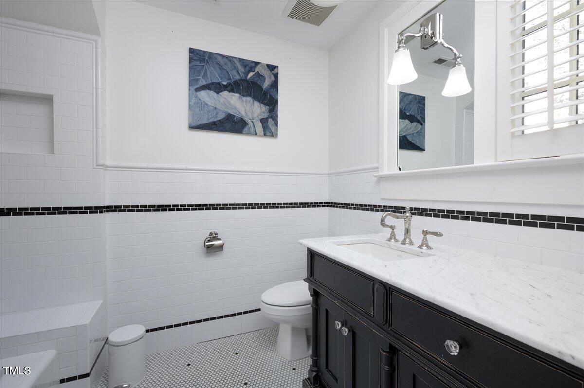 2412 Beechridge Road Raleigh, NC 27608 - Photo 16 of 39 a bathroom with a sink a toilet and mirror