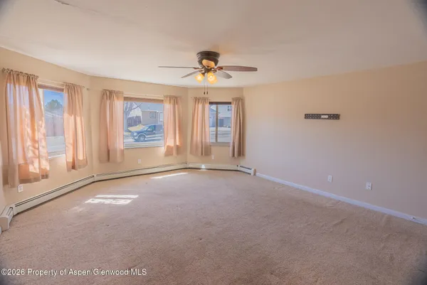 an empty room with windows and ceiling fan