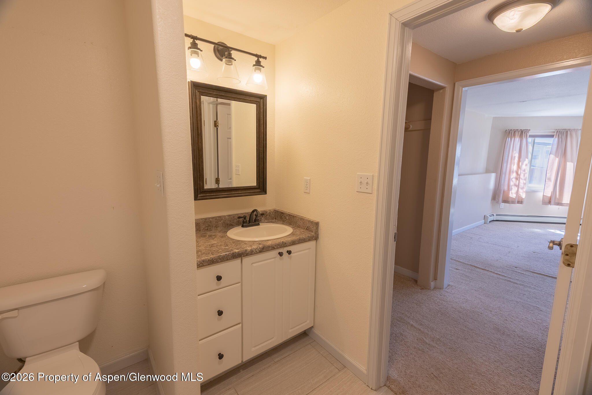 1558 East 12th Street Rifle, CO 81650 - Photo 7 of 25 a bathroom with a toilet a sink and mirror