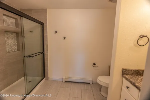 a bathroom with a granite countertop toilet and a shower