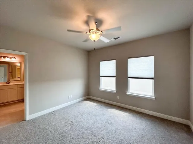 an empty room with chandelier fan and windows