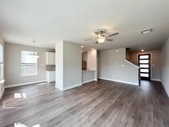 a view of an empty room with window and wooden floor