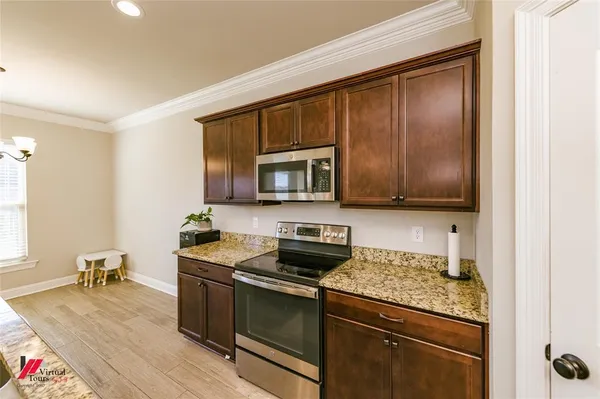 a kitchen with stainless steel appliances granite countertop a stove a sink and a microwave