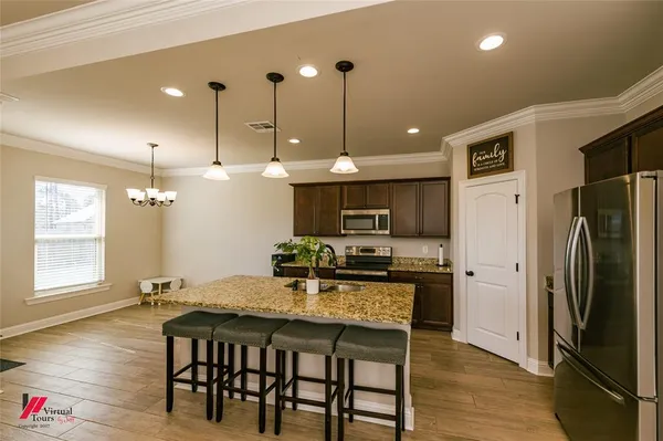 a kitchen with kitchen island a refrigerator a stove a dining table and chairs with wooden floor