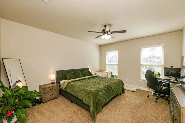 a bedroom with a bed a computer on the desk and chair