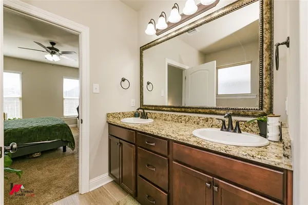 a en suite bathroom with a granite countertop sink and a mirror