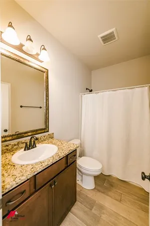 a bathroom with a granite countertop sink a toilet and a mirror