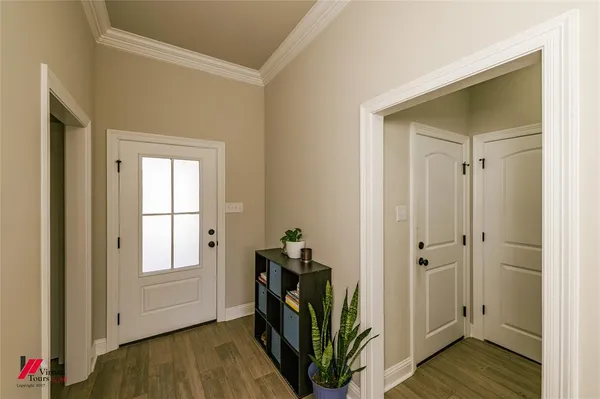 a view of a hallway to a room with wooden floor and closet