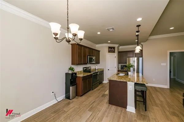 a kitchen with stainless steel appliances granite countertop cabinets a stove top oven and chandelier