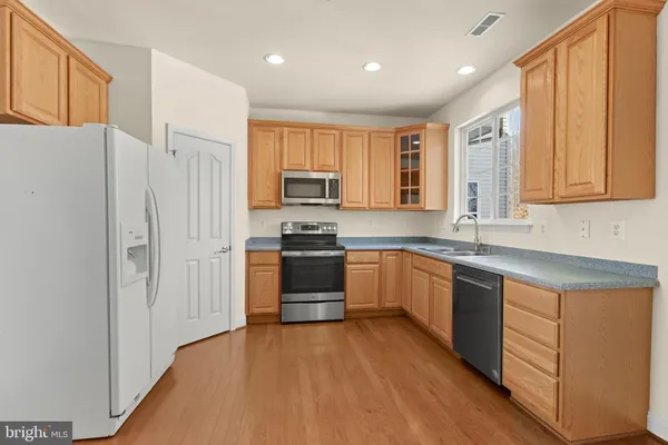 a kitchen with stainless steel appliances granite countertop a refrigerator a sink dishwasher a stove and white countertops with wooden floor