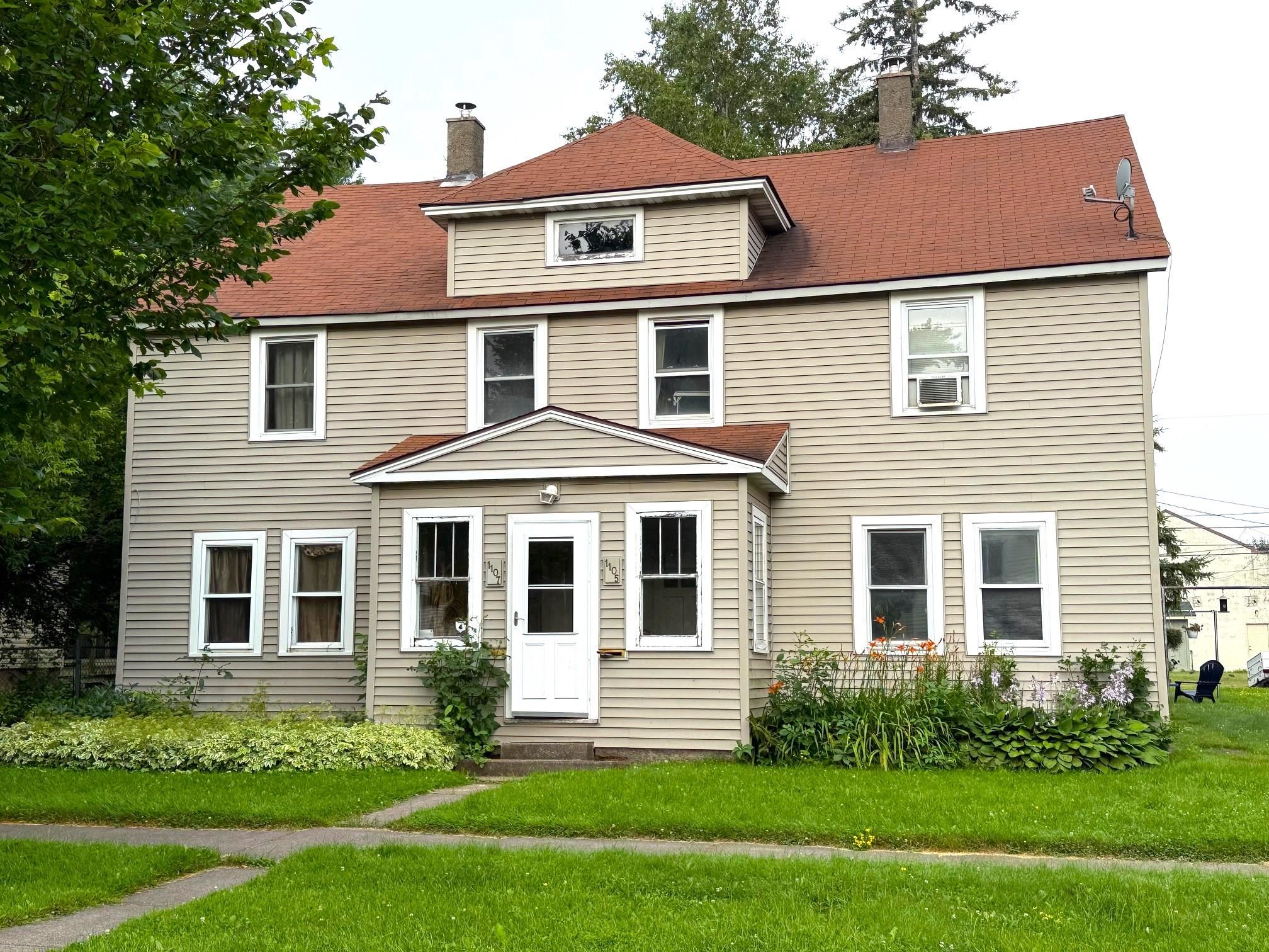 American foursquare style home featuring a chimney, a front lawn, and entry steps