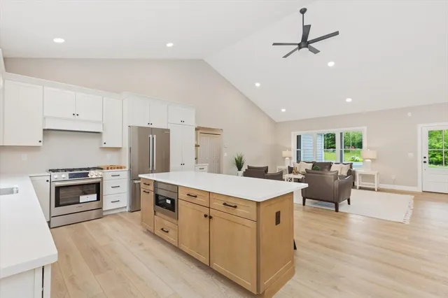 a kitchen with a stove a sink a kitchen island with chairs and wooden floor