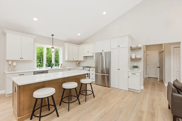 a kitchen with stainless steel appliances a dining table chairs refrigerator and sink