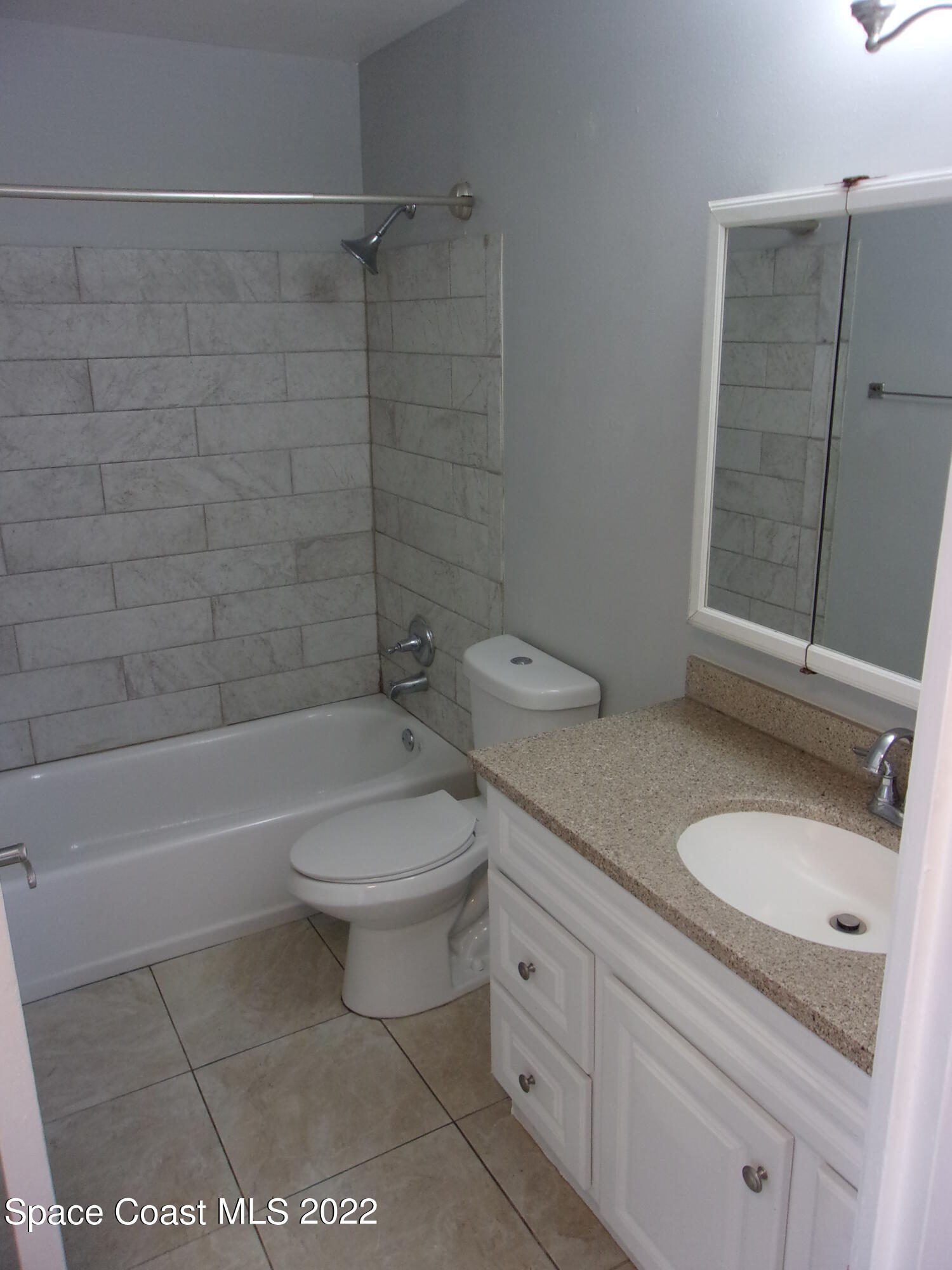 1050 North Fiske Boulevard, Unit 406 Cocoa, FL 32922 - Photo 10 of 11 a bathroom with a granite countertop toilet a sink and bathtub