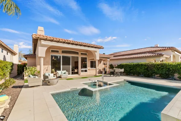 a front view of a house with swimming pool and furniture